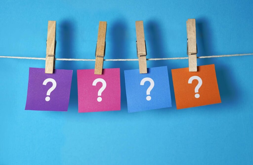 Colorful cards with question marks on them hanging from a string attached with clothespins.